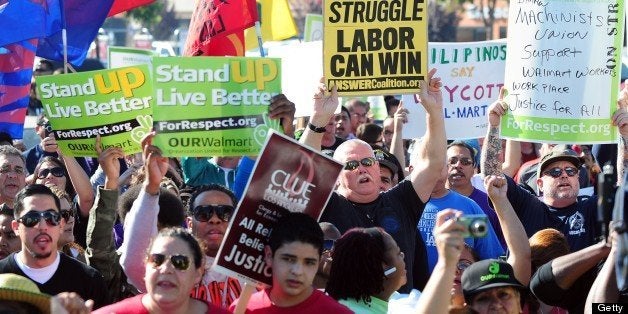 Walmart employees and their supporters protest in a parking lot after they were asked to move from the side of the front entrance to a Walmart store in Paramount, California on November 23, 2012. Unhappy Walmart employees are protesting across the US, seeking to make their demands for better pay and benefits more visible to the Americans flocking to the Black Friday shopping frenzy. AFP PHOTO / Frederic J. BROWN (Photo credit should read FREDERIC J. BROWN/AFP/Getty Images)