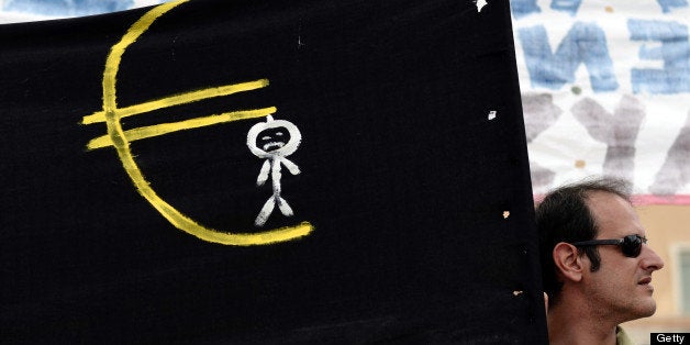A demonstrator stands next to a banners showing a character hanged on a Euro symbol during a demonstration on July 16, 2013 a