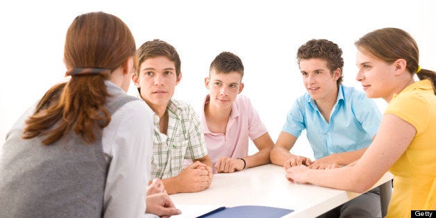 Group of adolescents sitting at a table with their trainer