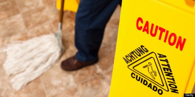 Service Industry: Caution sign and man mopping retail store floor