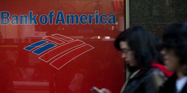 A woman checks a mobile device as she walks past a Bank of America Corp. branch in New York, U.S., on Tuesday, March 5, 2013. The six largest U.S. banks may return almost $41 billion to investors in the next 12 months, the most since 2007, as regulators conclude firms have amassed enough capital to withstand another economic shock. Photographer: Victor J. Blue/Bloomberg via Getty Images