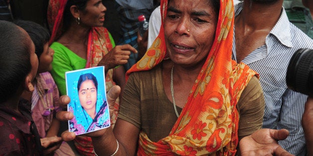A Bangladeshi woman shows a portrait of her missing daughter in-law, believed trapped in the rubble following the collapse of