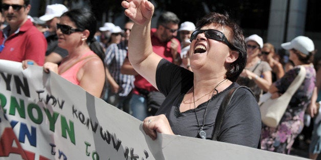 An employee shouts towards the ministry of labour in Athens during a protest march by civil servants on August 5, 2013. Greece must axe 4,000 state jobs by the end of the year and relocate 25,000 civil servants to support understaffed parts of its vast bureaucracy. AFP PHOTO/ LOUISA GOULIAMAKI (Photo credit should read LOUISA GOULIAMAKI/AFP/Getty Images)