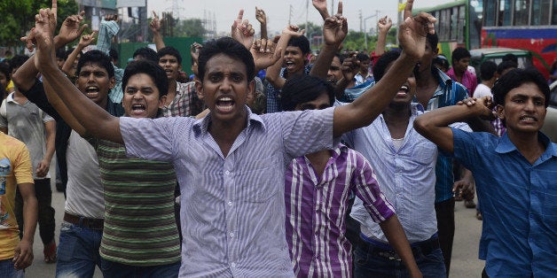 Bangladeshi garment workers shout slogans during a protest in Dhaka on September 23, 2013. Angry Bangladeshi garment workers blocked roads, set factories alight and clashed with police for a third day as protests demanding a minimum monthly wage of USD 100 spread outside the capital Dhaka. AFP PHOTO/ Munir uz ZAMAN (Photo credit should read MUNIR UZ ZAMAN/AFP/Getty Images)