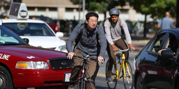CAMBRIDGE, MA - OCTOBER 5: Two bicyclists weave through traffic near MIT, one of whom is not wearing a helmet. (Photo by John