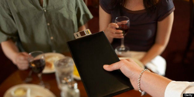 Waitress handing bill to couple in restaurant