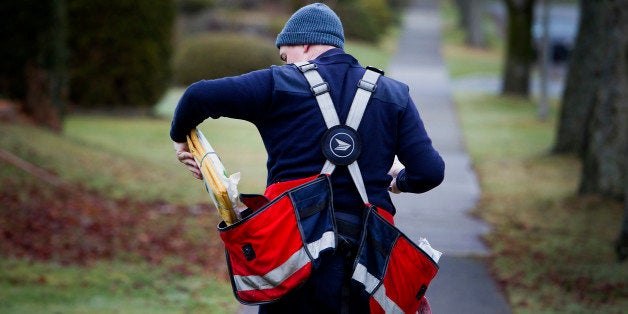 A Canada Post letter carrier puts packages in a bag while delivering mail by foot to houses in Vancouver, British Columbia, C