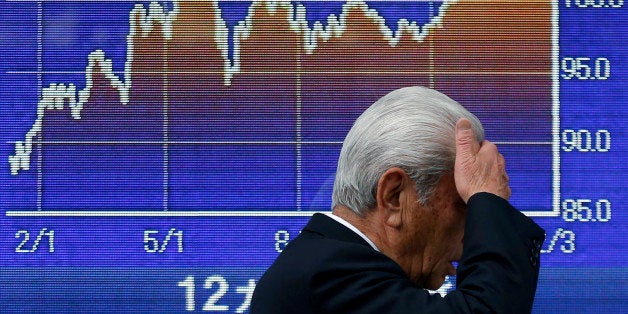 A pedestrian walks past an electronic stock board displaying a graph of the 12-month movement of the exchange rate of the yen against the U.S. dollar outside a securities firm in Tokyo, Japan, on Tuesday, Feb. 4, 2014. Japans Topix index headed for its biggest drop in eight months after the yen surged against the dollar as investors shunned risk assets amid concern about the global economic outlook. Photographer: Kiyoshi Ota/Bloomberg via Getty Images