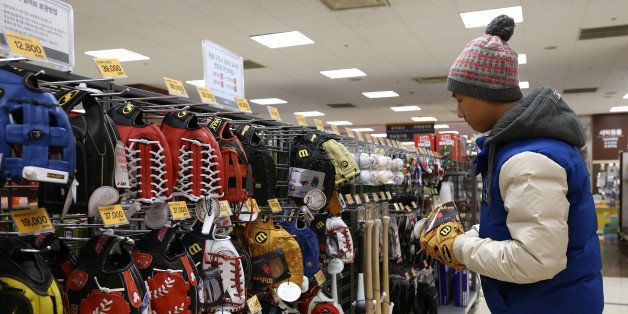 A customer tries out a Wilson Sporting Goods Co. baseball glove at an E-Mart Co. store, a subsidiary of Shinsegae Co., in Incheon, South Korea, on Saturday, Dec. 21, 2013. Consumer prices climbed 0.9 percent in November from a year earlier after a 0.7 percent increase in October that was the smallest gain since July 1999. Photographer: SeongJoon Cho/Bloomberg via Getty Images
