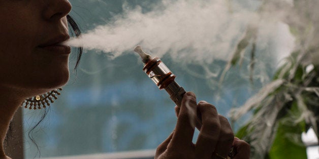 Ilona Orshansky, owner of Brooklyn Vaper, uses a vaporizer, also known as an e-cigarette, in her shop in the Brooklyn borough of New York, U.S., on Saturday, Feb. 8, 2014. Bloomberg Industries projects total U.S. e-cigarette sales could reach $1.5 billion this year. Photographer: Timothy Fadek/Bloomberg via Getty Images