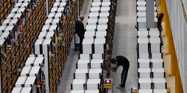 Employees process customer orders ahead of shipping at one of Amazon.com Inc.'s fulfillment centers in Rugeley, U.K., on Monday, Dec. 2, 2013. Online retailers in the U.K. are anticipating their busiest day as shoppers flush with end-of-month pay-checks seek Christmas deals on the Web. Photographer: Simon Dawson/Bloomberg via Getty Images