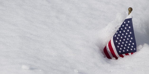 An American flag is covered with snow at Arlington National Cemetery in Arlington, Virginia, on January 27, 2011, the day after a snowstorm dropped 5-8 inches of snow in the Washington, DC, region. AFP PHOTO / Saul LOEB (Photo credit should read SAUL LOEB/AFP/Getty Images)