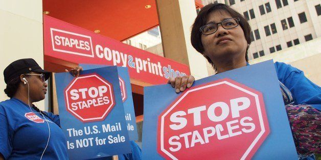 US postal workers demonstrate outside a Staples store in Los Angeles, California, April 24, 2014. Postal workers in 27 states protested against a partnership between the US Postal Service and office supply company Staples Inc. to run postal counters at its retail stores. AFP PHOTO / ROBYN BECK (Photo credit should read ROBYN BECK/AFP/Getty Images)