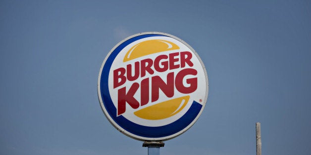 Burger King Worldwide Inc. signage stands outside a restaurant in Peoria, Illinois, U.S., on Tuesday, Aug. 26, 2014. Burger King Worldwide Inc. agreed to acquire Tim Hortons Inc. for about C$12.5 billion ($11.4 billion) in a deal that creates the third-largest fast-food company and moves its headquarters to Canada. Photographer: Daniel Acker/Bloomberg via Getty Images