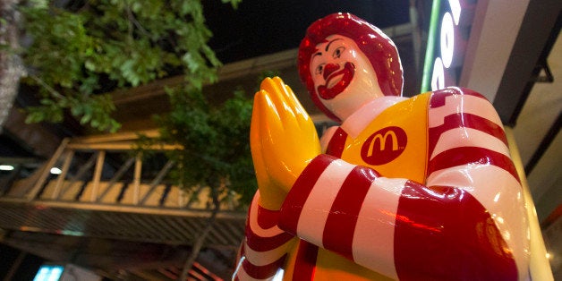 People walk near a McDonald's restaurants in Bangkok, Thailand, Friday, May 30, 2014. The burger chain's famous golden arches have become part of the iconography of anti-coup protests and it is warning activists to "cease and refrain" from using its trademark. (AP Photo/Sakchai Lalit)