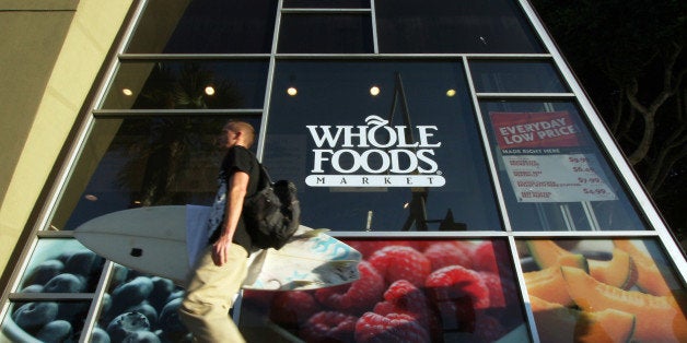 In this Oct. 31, 2011 photo, a man carries a surfboard past a Whole Foods store in Santa Monica, Calif. Whole Foods Market Inc., reports quarterly financial results Wednesday, Nov. 2, 2011, after the market close.(AP Photo/Reed Saxon)