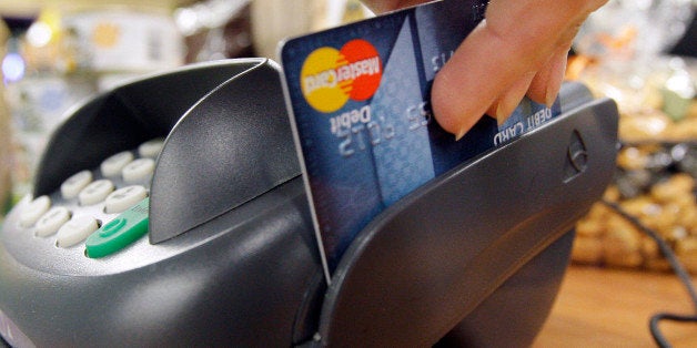 FILE - In this Nov. 2, 2009 file photo, a customer swipes a MasterCard debit card through a machine while checking-out at a shop in Seattle. For many, part of the strategy for keeping on budget includes a plan to leave the credit cards at home and use a debit card at the checkout. (AP Photo/Elaine Thompson, file)