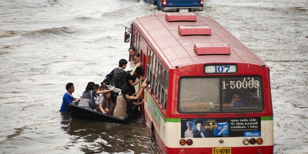 TO GO WITH AFP STORY BY RICHARD INGHAMCommuters alight from their boat as they board a bus in floodwaters in the Lat Phrao shopping and business district in Bangkok on November 8, 2011. Climate change is amplifying risks from drought, floods, storm and rising seas, threatening all countries but small island states, poor nations and arid regions in particular, UN experts warned on March 27, 2012. AFP PHOTO/ Nicolas ASFOURI (Photo credit should read NICOLAS ASFOURI/AFP/Getty Images)