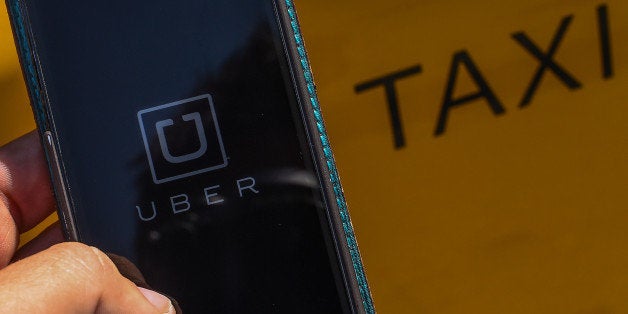 BARCELONA, SPAIN - JULY 01: In this photo illustration, the new smart phone app 'Uber' logo is displayed on a mobile phone next to a taxi on July 1, 2014 in Barcelona, Spain. Taxi drivers in main cities strike over unlicensed car-halling services. Drivers say that is a lack of regulation behind the new app. (Photo Illustration by David Ramos/Getty Images)