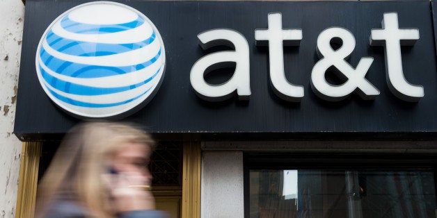 A pedestrian talks on a cell phone while walking past an AT&T Inc. store in New York, U.S., on Monday, Jan. 27, 2014. AT&T Inc. is scheduled to release earnings figures on Jan. 28. Photographer: Craig Warga/Bloomberg via Getty Images