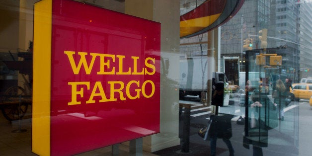 The reflections of pedestrians are seen in the window of a Wells Fargo & Co. bank branch in New York, U.S., on Monday, April 7, 2014. Wells Fargo & Co. is expected to release earnings figures on April 11. Photographer: Craig Warga/Bloomberg via Getty Images