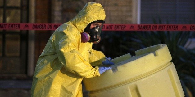 A hazmat worker moves a barrel while finishing up cleaning outside an apartment building of a hospital worker, Sunday, Oct. 1