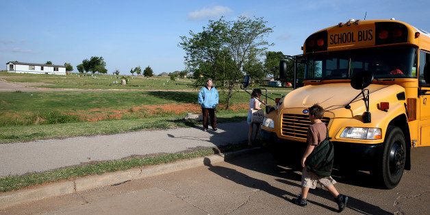 MOORE, OK - MAY 19: Janet Underwood (L) watches as her son and other children get on the school bus in front of what used to be a trailer park before it was destroyed almost one year ago by a tornado on May 19, 2014 in Moore, Oklahoma. One May 20, 2013 a two-mile wide EF5 tornado touched down in the town killing 24 people and leaving behind extensive damage to homes and businesses. (Photo by Joe Raedle/Getty Images)