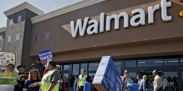 Shopper Jose Alvarez, right, carries out a newly-purchased television past protestors outside a Walmart store Friday Nov. 23,