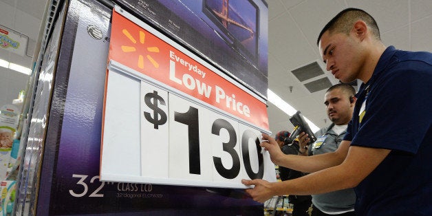 An employee lowers the price on televisions at the Walmart in the Crenshaw district of Los Angeles on Black Friday, November 29, 2013. US stocks Friday moved higher in a holiday-shortened session following better eurozone economic data and positive early assessments of 'Black Friday' shopping traffic by some leading retailers. AFP PHOTO / Robyn Beck (Photo credit should read ROBYN BECK/AFP/Getty Images)