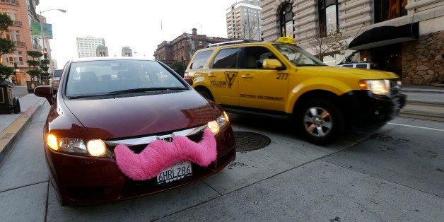 In this Jan. 4, 2013 photo, Lyft driver Nancy Tcheou waits in her car after dropping off a passenger as a taxi cab passes her in San Francisco. Fed up with traditional taxis, city dwellers are tapping their smartphones to hitch rides from strangers using mobile apps that allow riders and drivers to find each other. Internet-enabled ridesharing services such as Lyft, Uber and Sidecar are expanding rapidly in San Francisco, New York and other U.S. cities, billing themselves as a high-tech, low-cost alternative to cabs. (AP Photo/Jeff Chiu)