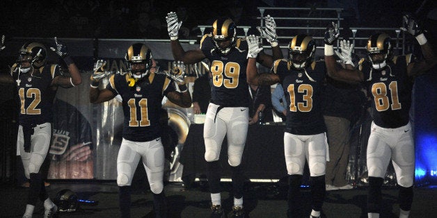 ADDS SIGNIFICANCE OF THE RAISED ARMS -- Members of the St. Louis Rams raise their arms in awareness of the events in Ferguson, Mo., as they walk onto the field during introductions before an NFL football game against the Oakland Raiders, Sunday, Nov. 30, 2014, in St. Louis. The players said after the game, they raised their arms in a "hands up" gesture to acknowledge the events in Ferguson. (AP Photo/L.G. Patterson)