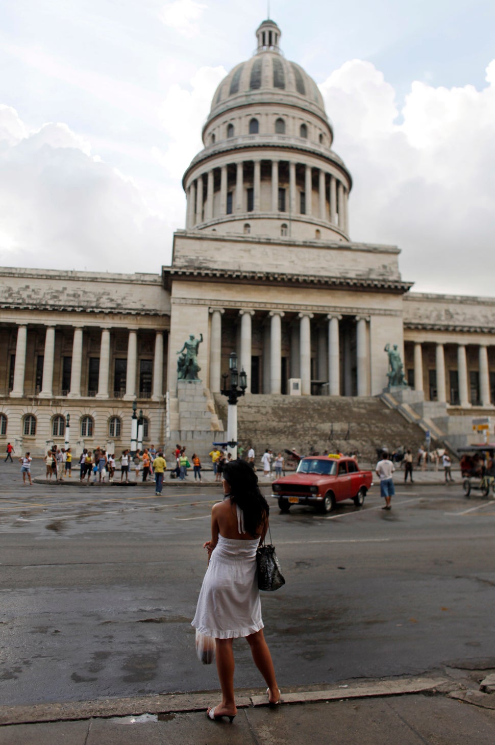 2010 - A woman waits for a bus in front of the Capitol building in Havana.