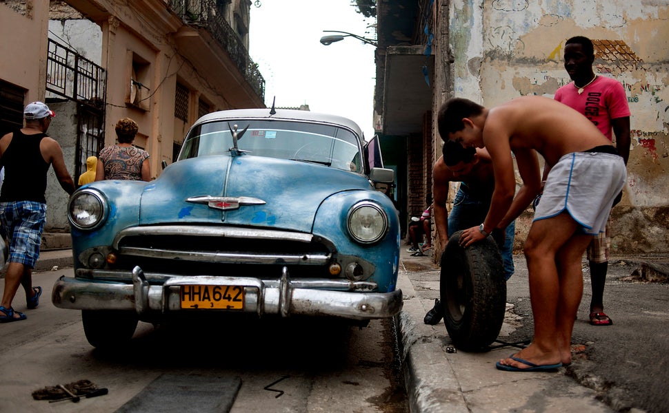 2012 - Men change the tire on an old Chevrolet in Havana.