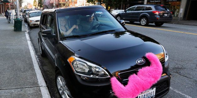 In this March 12, 2014 photo, passenger Katie Baranyuk, left, and Dara Jenkins, right, a driver for the ride-sharing service Lyft, perform Lyft's trademark fist-bump as they pose for a photo after Baranyuk got a ride from Jenkins to downtown Seattle to meet friends after work. In a fight pitting upstart technology and traditional business, app-based ridesharing firms are fighting with taxi companies for supremacy in the Seattle market. (AP Photo/Ted S. Warren)