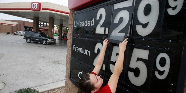 In this Friday, Dec. 12, 2014 photo, Quick Trip clerk Roxana Valverde adjusts the gas price sign numbers at a Tolleson, Ariz.