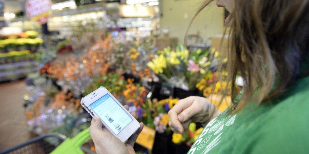 DENVER, CO. OCTOBER 28: Kaitlin Myers a shopper for Instacart studies her smart phone as she shops for a customer at Whole Foods in Denver. Myers receives a grocery list for a shopper and then completes the shopping on Tuesday, October 28, 2014. (Denver Post Photo by Cyrus McCrimmon)