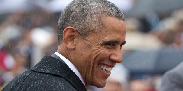 U.S. President Barack Obama smiles in the rain as he arrives for Republic Day in New Delhi, India, Monday, Jan. 26, 2015. Obama on Monday took in a grand display of Indian military hardware, marching bands and elaborately dressed camels, becoming the first American leader to be honored as chief guest at Indiaâs annual Republic Day festivities. (AP Photo/Carolyn Kaster)