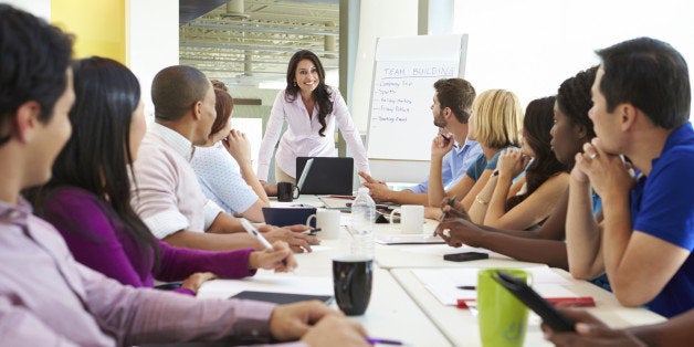 Businesswoman Addressing Meeting Around Boardroom Table In Smart/Casual Dresswear