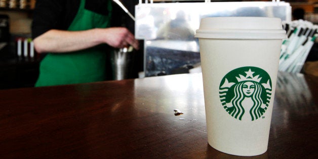 A Starbucks drink waits for a customer to pick it up as barista Josh Barrow prepares another at left, Friday, April 27, 2012, in Seattle. Starbucks Corp. perked up its net income by 18 percent in its fiscal second quarter, as more customers visited its cafes in most parts of the world. (AP Photo/Ted S. Warren)