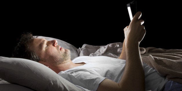 male in bed browsing the internet late at night with a tablet