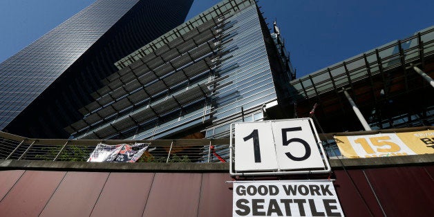 A sign that reads "15 Good Work Seattle" is displayed below Seattle City Hall, right, and the Columbia Center building, left, Monday, June 2, 2014, after the Seattle City Council passed a $15 minimum wage measure. (AP Photo/Ted S. Warren)