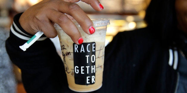 Larenda Myres holds an iced coffee drink with a "Race Together" sticker on it at a Starbucks store in Seattle, Wednesday, Mar