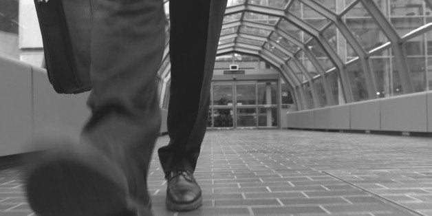 Businessman walking and holding briefcases, low section (B&W)