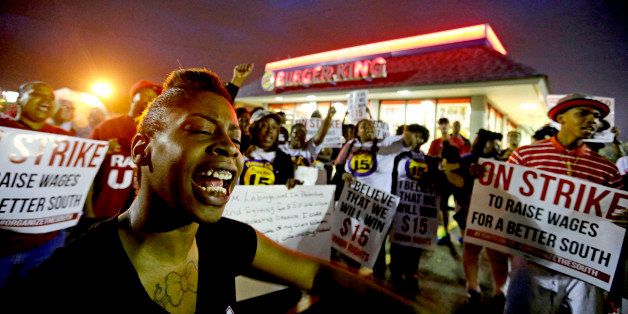 Carmen Burley-Rawls, left, chants during a protest outside a Burger King restaurant by fast-food workers and activists calling for the federal minimum wage to be raised to $15, Wednesday, April 15, 2015, in College Park, Ga. Organizers say they chose April 15, tax day, to demonstrate because they want the public to know that many low-wage workers must rely on public assistance to make ends meet. (AP Photo/David Goldman)