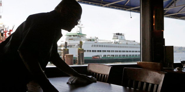 FILE - In this May 14, 2014 file photo, a worker busses a table at Ivar's Acres of Clams restaurant in view of a nearby docke