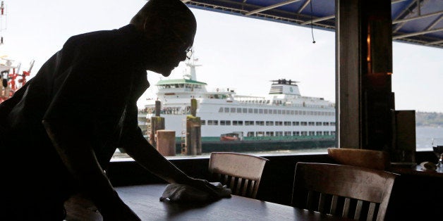 FILE - In this May 14, 2014 file photo, a worker busses a table at Ivar's Acres of Clams restaurant in view of a nearby docked state ferry on the Seattle waterfront. Interest in income inequality is at the forefront in public debate, with political figures from Sen. Elizabeth Warren on the left to Republican presidential prospect Jeb Bush on the right decrying the widening gap between the wealthy and everyone else. But Americans arenât nearly as fascinated by the issue as their leaders seem to be. (AP Photo, File)