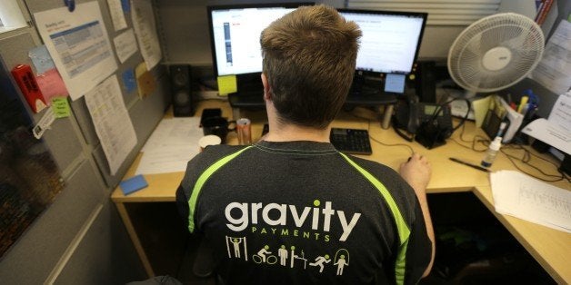 Austin Roos, a support team supervisor, works at his desk Wednesday, April 15, 2015, at Gravity Payments, a credit card payment processor based in Seattle. Gravity CEO Dan Price told his employees this week that he was cutting his roughly $1 million salary and using company profits so they would each earn a base salary of $70,000, to be phased in over three years. (AP Photo/Ted S. Warren)