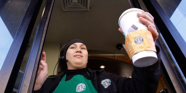 Starbucks barista Alex Igarta hands a coffee drink to a customer from a drive-up window at a store near the company's corpora