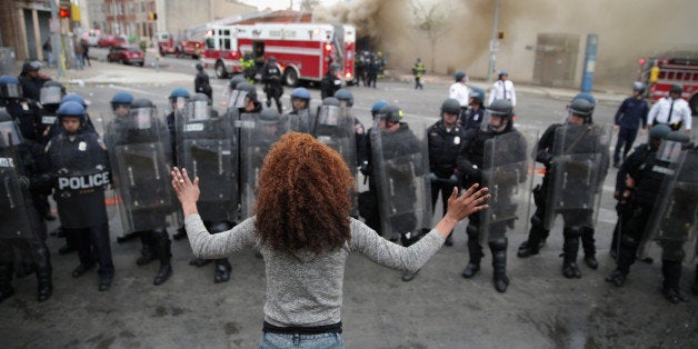 BALTIMORE, MD - APRIL 27: A woman faces down a line of Baltimore Police officers in riot gear during violent protests following the funeral of Freddie Gray April 27, 2015 in Baltimore, Maryland. Gray, 25, who was arrested for possessing a switch blade knife April 12 outside the Gilmor Homes housing project on Baltimore's west side. According to his attorney, Gray died a week later in the hospital from a severe spinal cord injury he received while in police custody. (Photo by Chip Somodevilla/Getty Images)