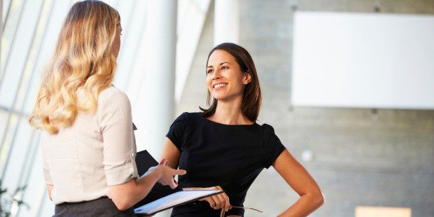 Two Businesswomen Having Informal Meeting In Modern Office Smiling